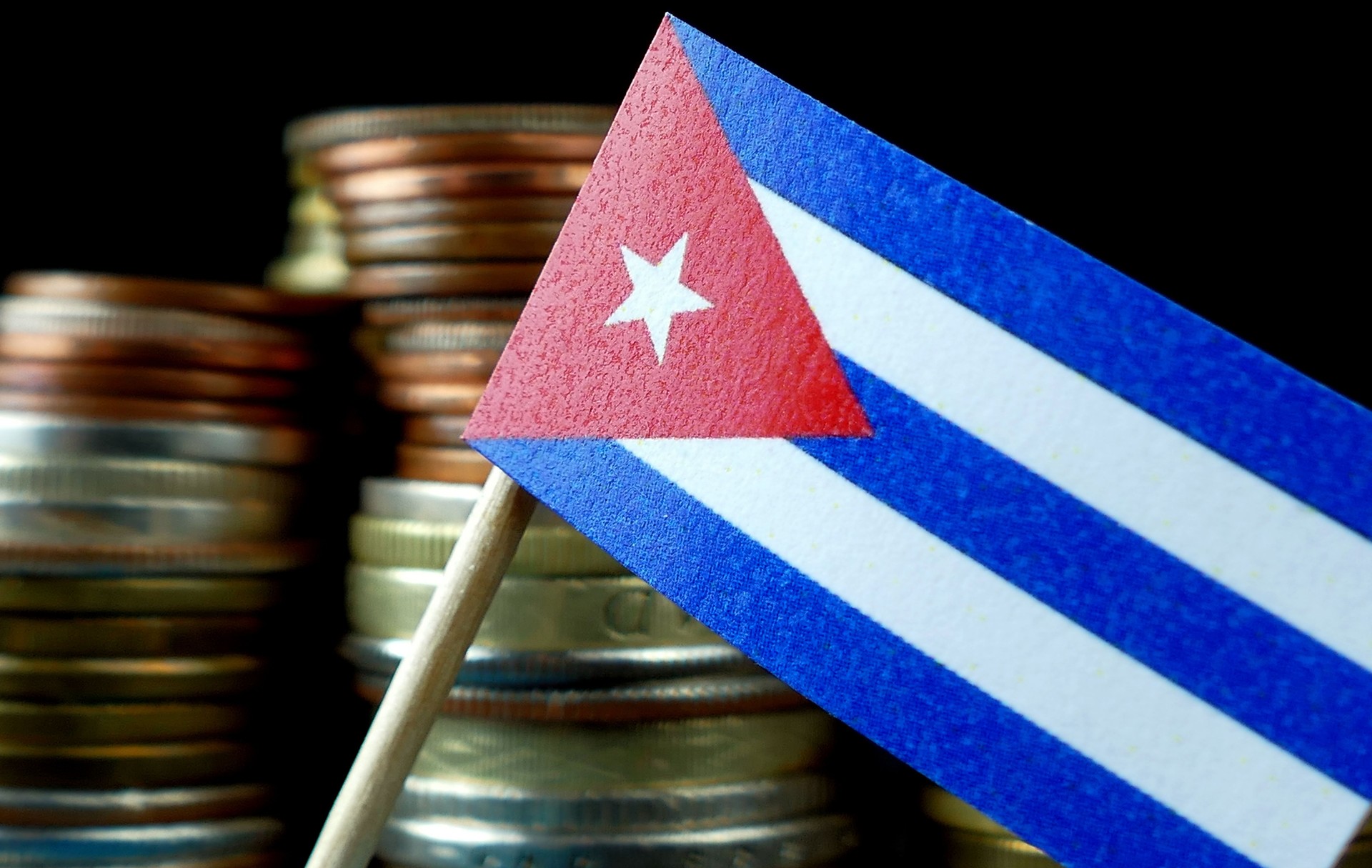 Cuba flag waving with stack of money coins macro