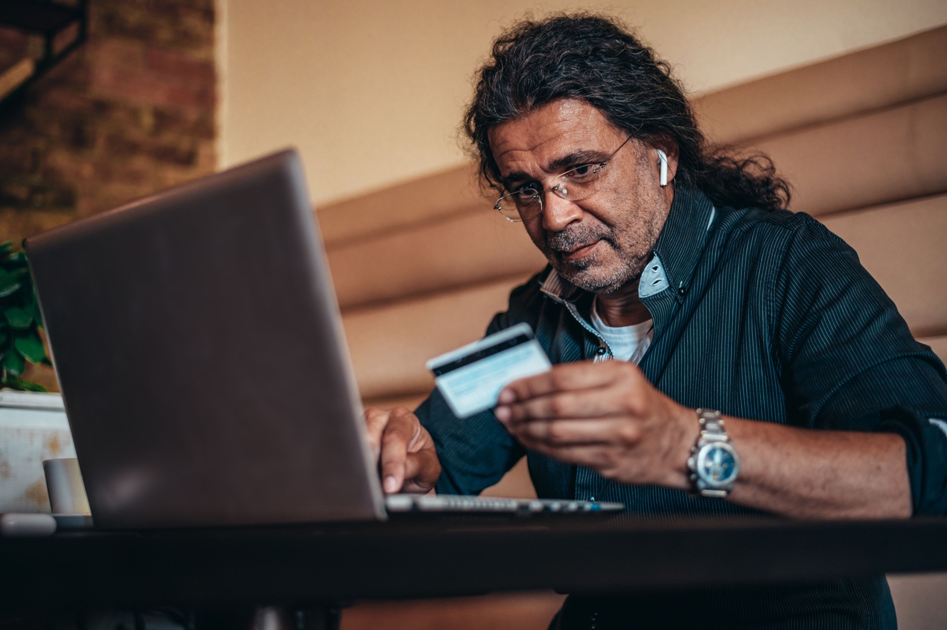 Senior hispanic cuban men using laptop and a credit card while online shopping